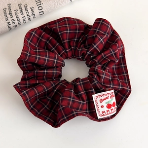 Close-up of red plaid scrunchie fabric with a sweet cherry woven label detail