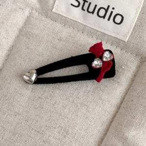 Macro shot of vintage velvet hair clip with red bow, rhinestones and heart charms