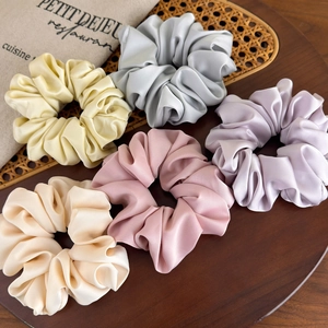 5-pack large satin scrunchies in pastel colors on a wooden tray with elegant folds