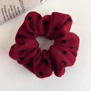 Detailed close-up of dark red wool scrunchie with black polka dots and embroidery