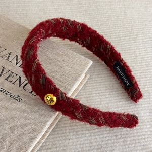 Detail of red tweed headband with golden heart button and handmade label on soft fabric