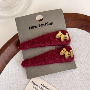 Detailed view of burgundy knit hair clips with golden horse motifs on display card