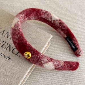 Detail of red and cream plaid plush headband with golden emblem and handmade label