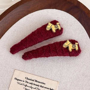 Close-up of handmade burgundy knit hair clips with golden dala horse metal accents