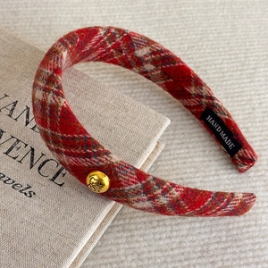 Detail view of red plaid headband with gold metal button and handmade woven label