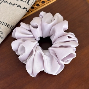 Detailed view of lavender satin scrunchie with silky luster on wooden background