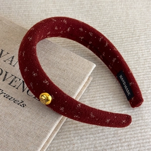 Detail view of retro wine red plush headband with gold label and handmade woven tag