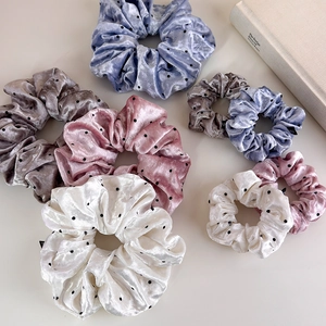 Detailed view of velvet polka dot scrunchies in assorted sizes and soft colors