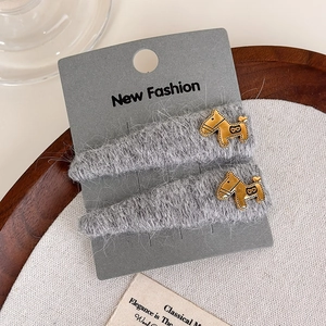Close-up of gray knitted hair clips with golden puppy charms and heart details