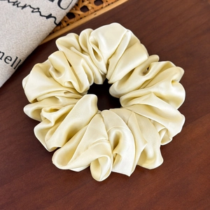 Close-up of champagne gold satin scrunchie with silky texture on wooden background