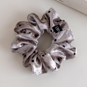 Detail view of silver velvet polka dot scrunchie with soft sheen and hand label