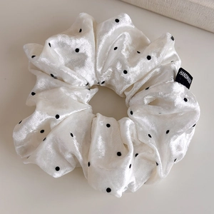 Macro detail of velvet polka dot scrunchie with handmade label and soft texture