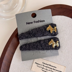 Detail of dark grey plush hair clips with golden dog charms on a display card