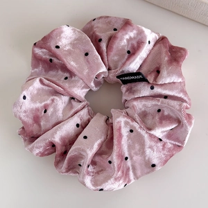 Detail of pink velvet polka dot scrunchie with handmade label and soft texture