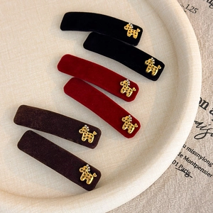 Velvet hair clips set with golden dog emblems in black, red, and brown on a beige tray