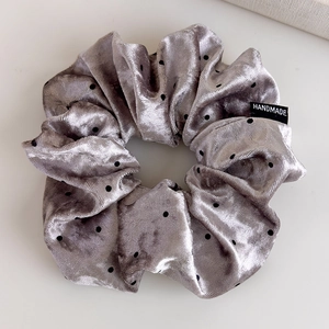 Detail of silver grey velvet scrunchie with black polka dots and handmade textile label