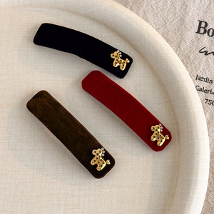Detail of velvet rectangle hair clips with golden poodle charms in three rich colors
