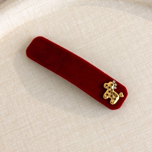 Macro view of red velvet hair clip with golden poodle charm and sparkling rhinestones