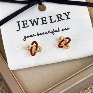 Detail of red enamel and gold cubic zirconia interlocking knot earrings in a gift box
