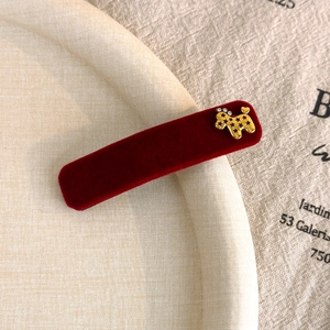 Close-up of a burgundy velvet hair clip with a golden poodle charm and rhinestones
