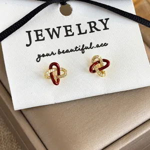 Macro shot of red concentric knot stud earrings with gold zircon details on jewelry box