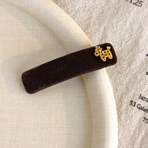 Detail of velvet hair clip with golden poodle charm and rhinestone embellishments