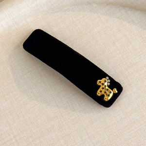 Macro shot of black velvet hair clip with gold poodle charm and sparkling rhinestones