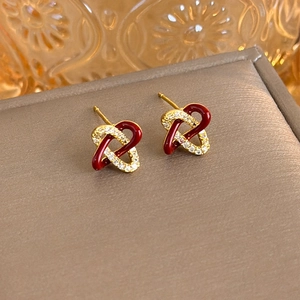 Macro shot of red enamel and zircon interlocking heart studs on a golden jewelry box