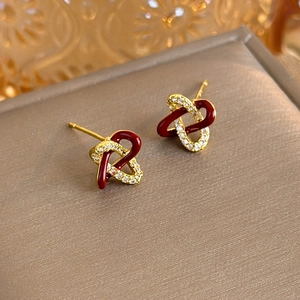 Macro detail of interlocking red enamel heart earrings with micro-set zircon stones