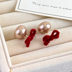 Detailed macro view of vintage red velvet bow earrings with champagne pearl studs
