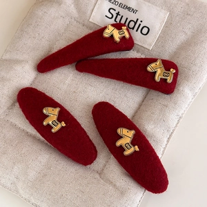 Set van vier rode pluchen haarspelden met decoratieve gouden pony-accenten op stof