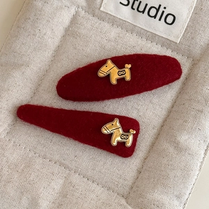 Details van rode pluche haarspelden met gouden paardbedels op een beige linnen doek