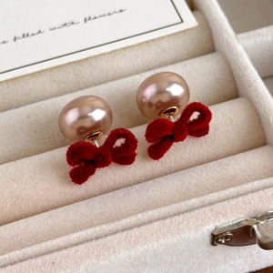 Close-up of red velvet bow and champagne pearl earrings in a velvet jewelry box