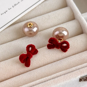 Close-up of red velvet bow earrings with champagne faux pearls on a jewelry box