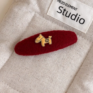 Detailopname van bordeaux pluche haarklem met gouden pony versiering op beige canvas achtergrond