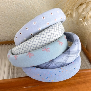 Pastel blue floral and plaid padded headbands collection displayed on a wooden tray