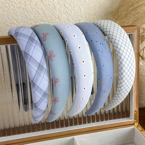 Detail view of five blue floral and plaid padded headbands in a wooden jewelry box