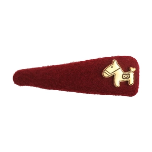 Detailopname van donkerrode vilten haarclip met een goudkleurig paardenembleem