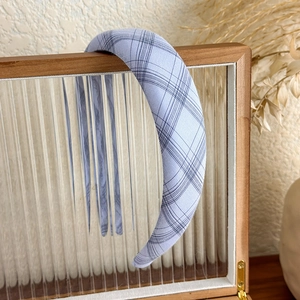 Detail of blue plaid padded headband hanging on a rustic wooden frame in a soft setting