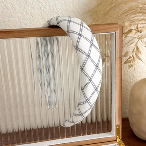 Gros plan d'un serre-tête en tissu à carreaux blancs sur une boîte à bijoux rétro