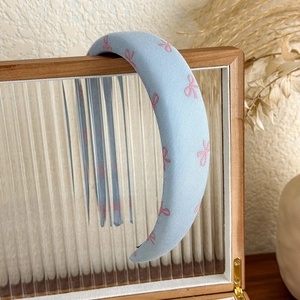 Detail of light blue padded headband featuring a cute pink bow pattern on knit fabric