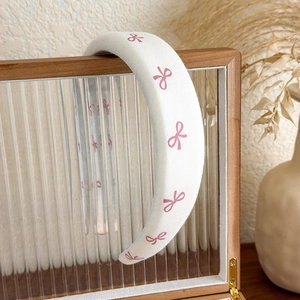 Détail d'un serre-tête rembourré blanc avec motifs de nœuds roses sur verre