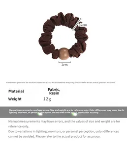 Détail du chouchou plissé marron avec une perle en résine de 2 cm sur fond blanc