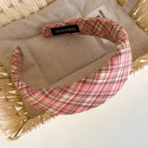 Detail view of handmade red and green plaid headband on a woven basket background