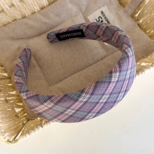 Close-up of purple plaid fabric headband featuring a black handmade label detail