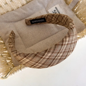 Detail of a brown plaid headband with handmade label in a cozy white woven basket