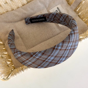 Macro detail of a plaid headband with blue and grey tartan fabric and handmade label