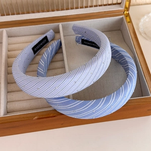 Détail de serre-têtes en tissu à rayures bleues avec strass dans une boîte à bijoux