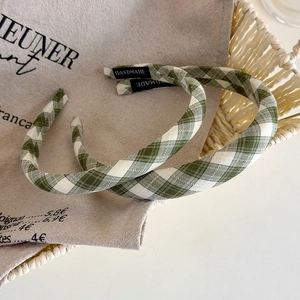 Set of two green gingham fabric headbands with handmade tags in a rustic woven basket
