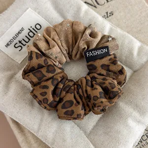 Detail of leopard print scrunchie with silver star charm and a fashion fabric label